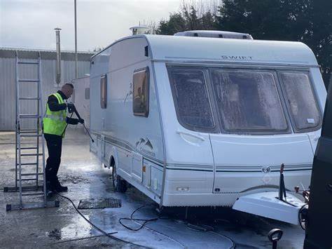 Man pressure washing exterior of a caravan